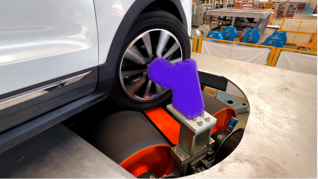 A car undergoing a vehicle inspection, with a device attached to its wheel in an industrial setting.